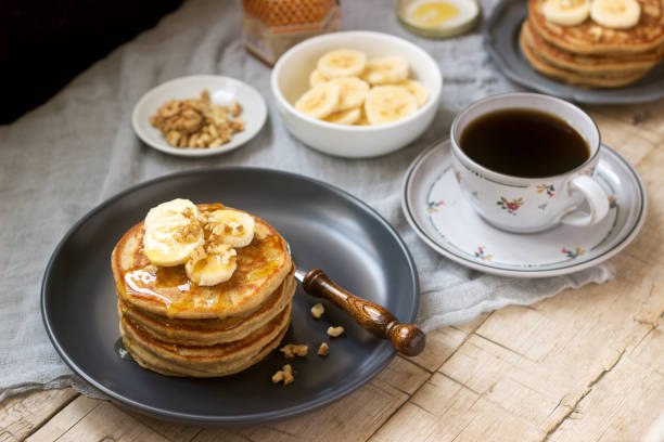Pancakes with banana, nuts and honey, served with tea. Rustic style, selective focus. banana pancakes